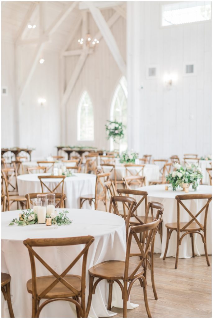 Elegant white wedding barn with wooden chairs and green flowers