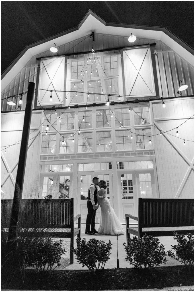 Couple kisses under bistro lights at their barn wedding in Texas