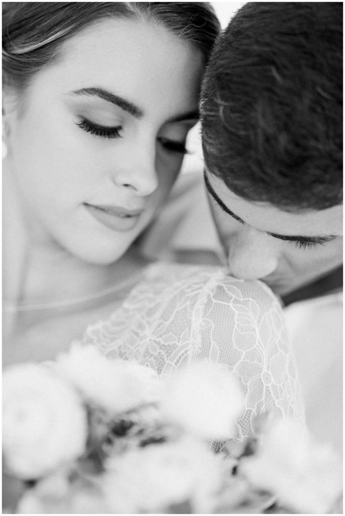 Intimate wedding couple photo of the groom kissing the bride on the shoulder - black and white