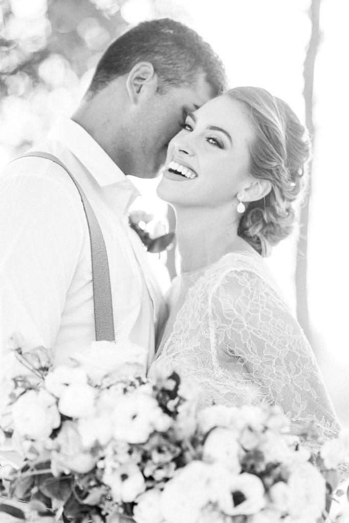 Black and white portrait of a couple in a lace dress with their bouquet in front