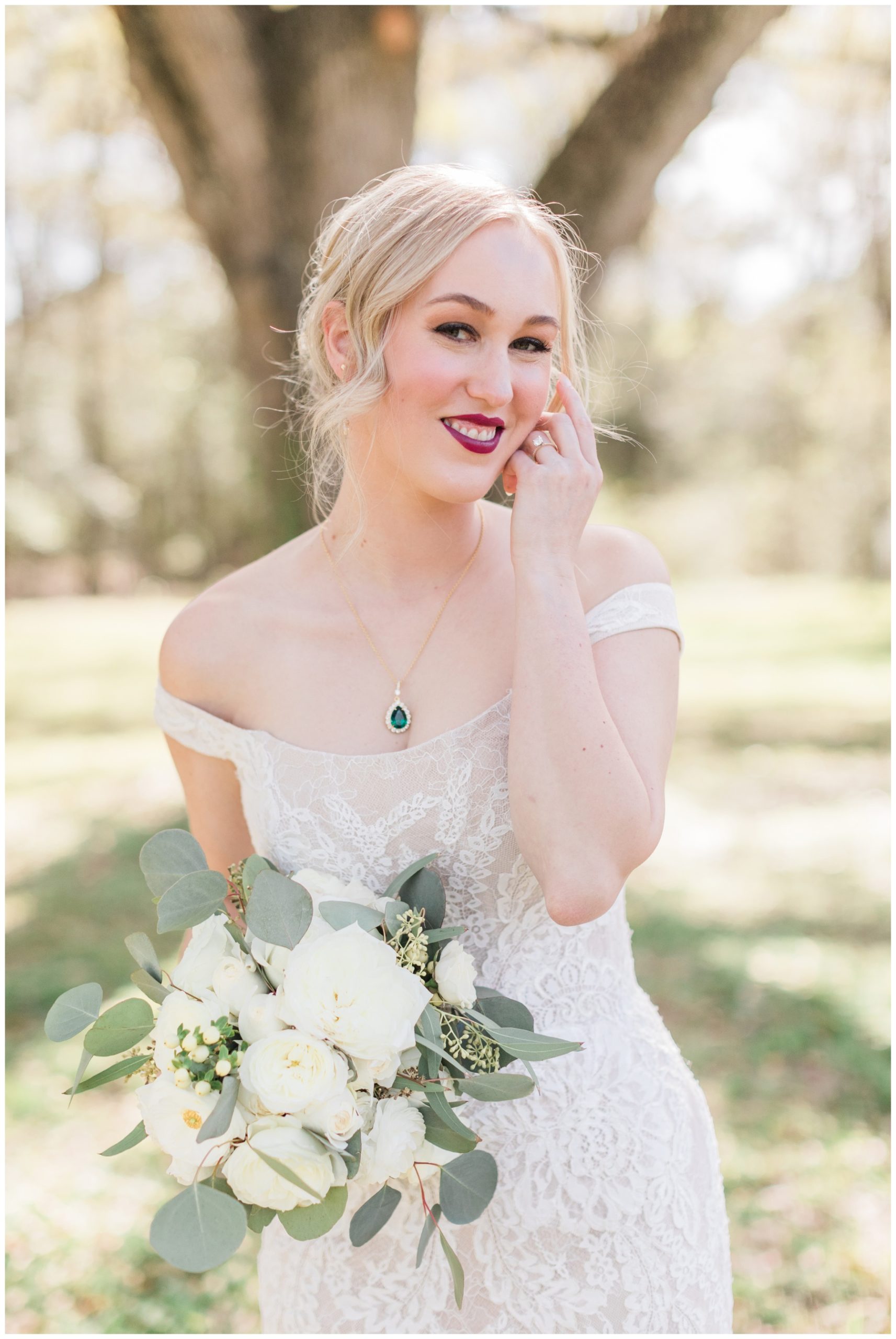 Bride wearing an off the shoulder lace wedding gown and a gold emerald necklace