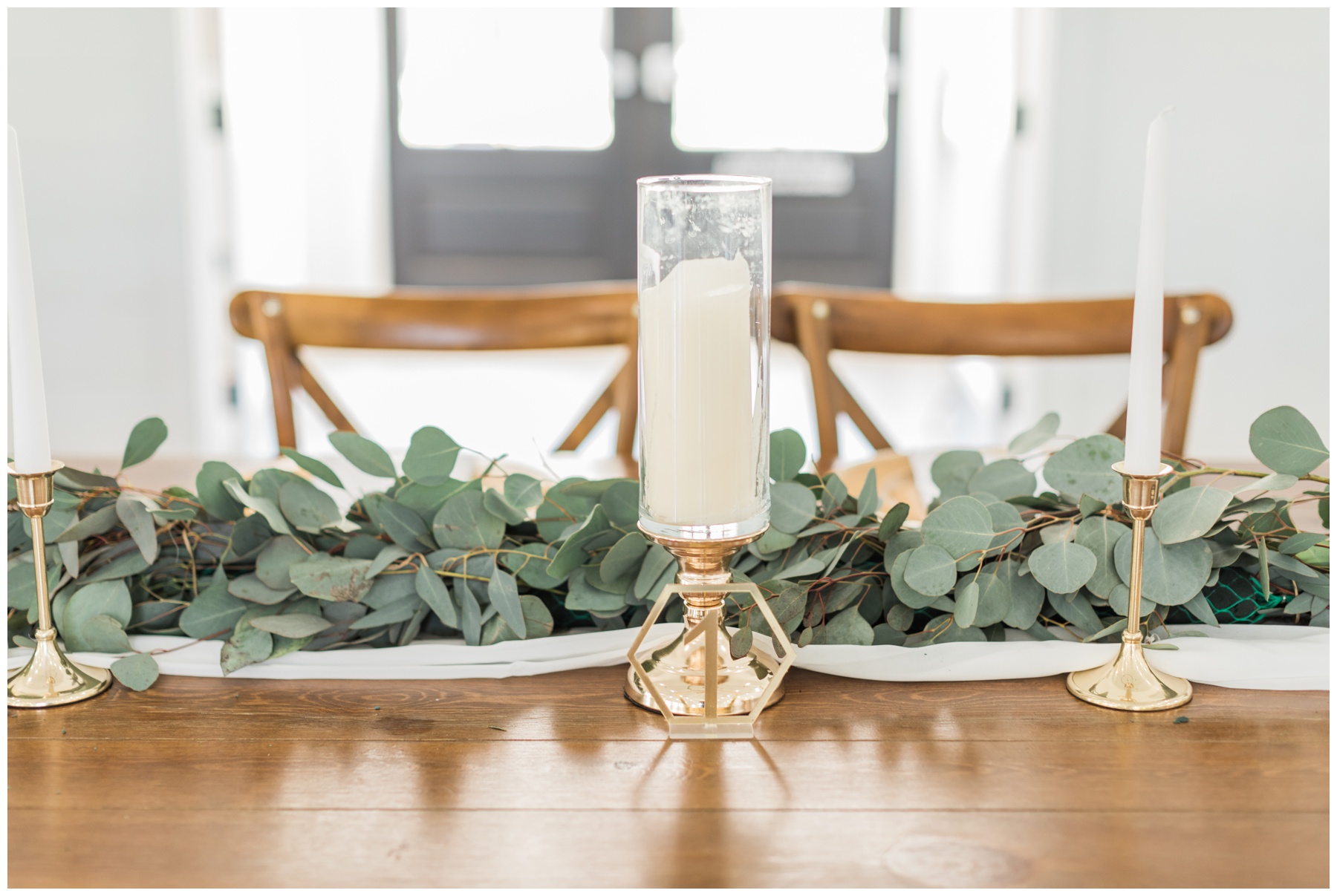 Gold plates, white and gold candles, and a eucalyptus runner for a modern wedding reception