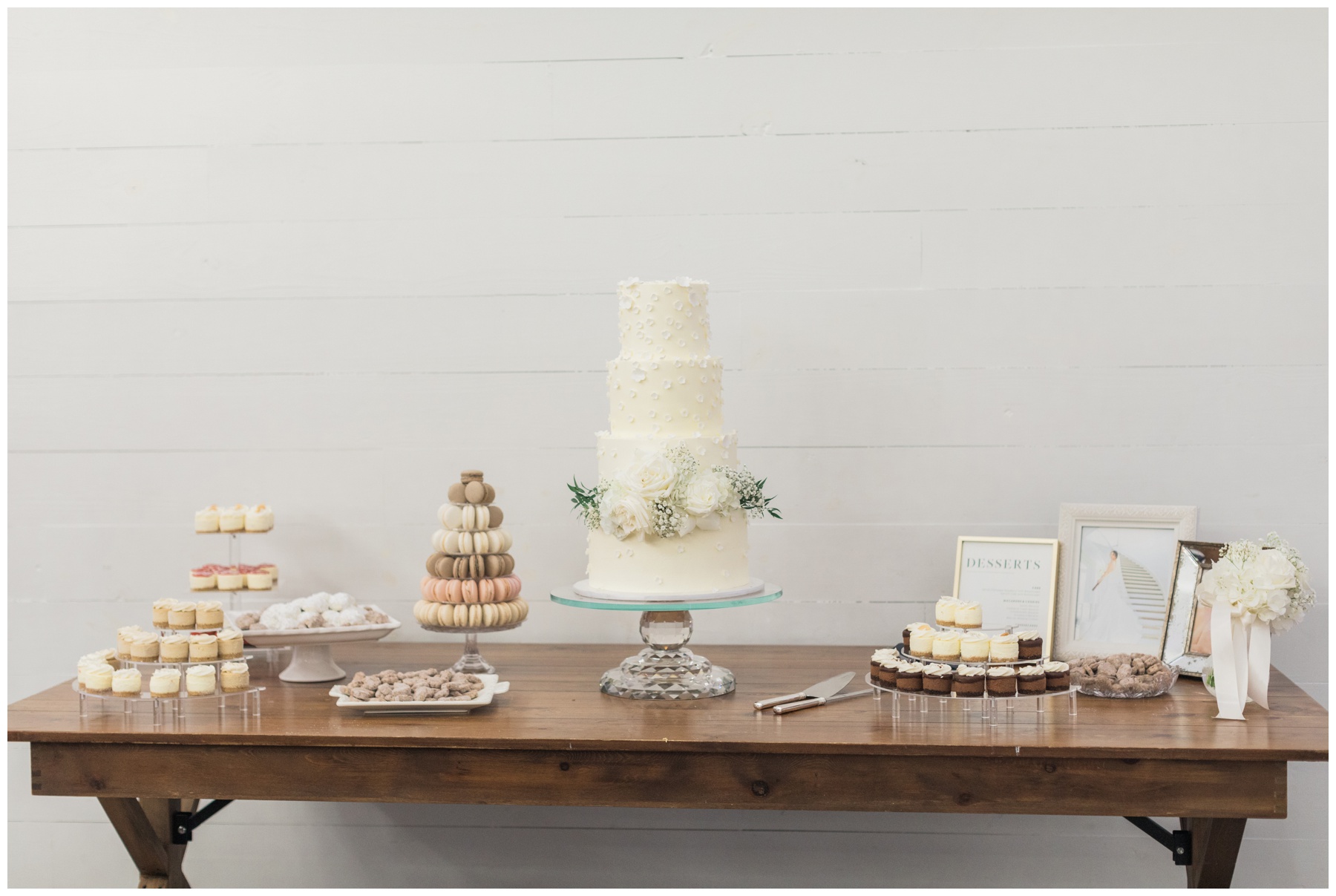 Dessert table with mini cheesecakes, macarons, Mexican wedding cookies, and a four-tiered cake at a Houston wedding