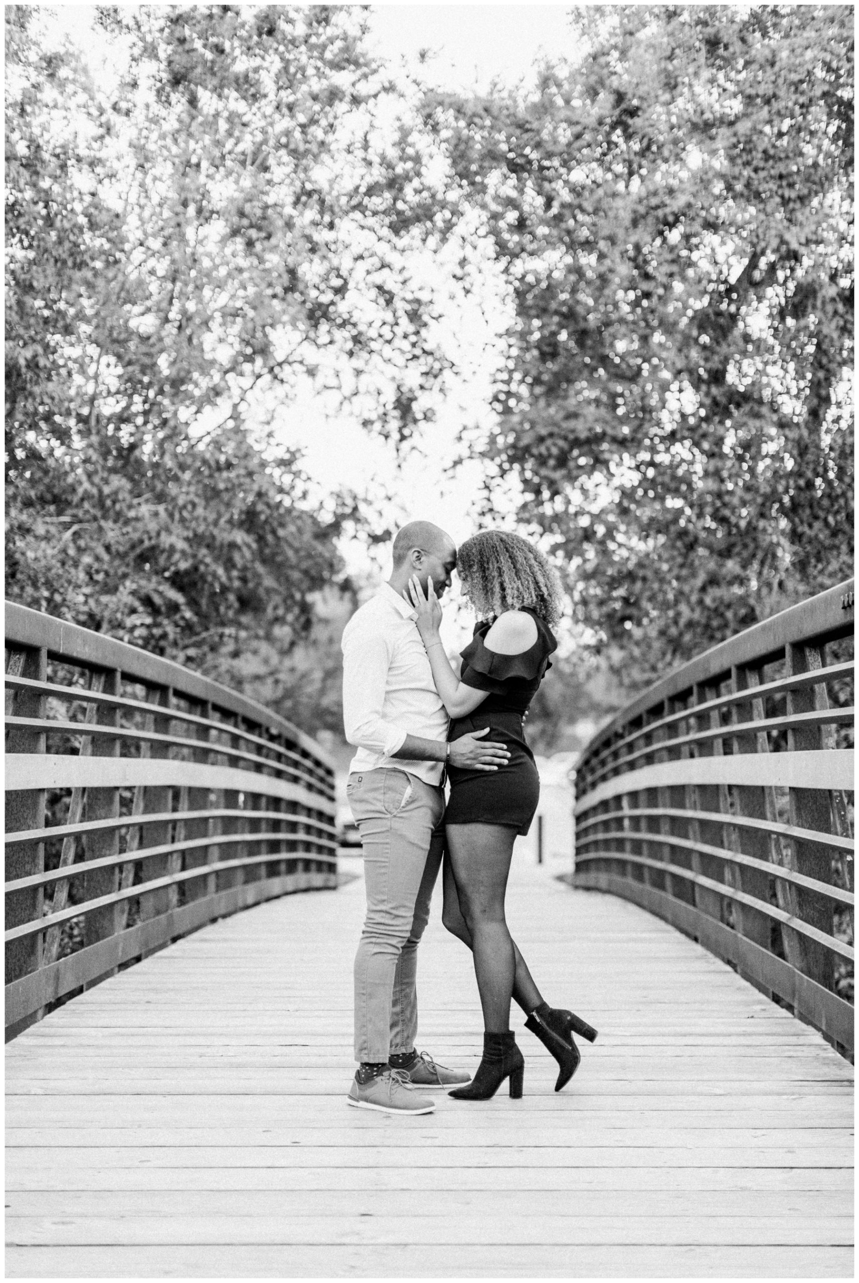Couple posing together on a bridge for their outdoor engagement session