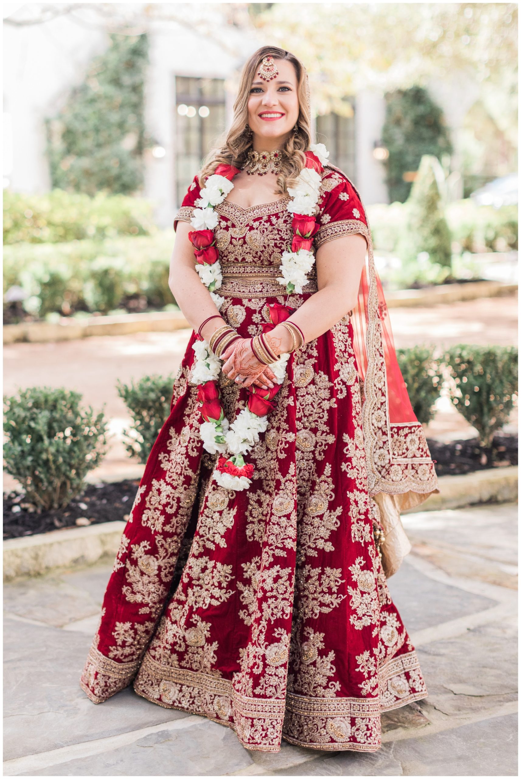Bride in a red and gold custom Indian wedding dress from Maharani Fashions