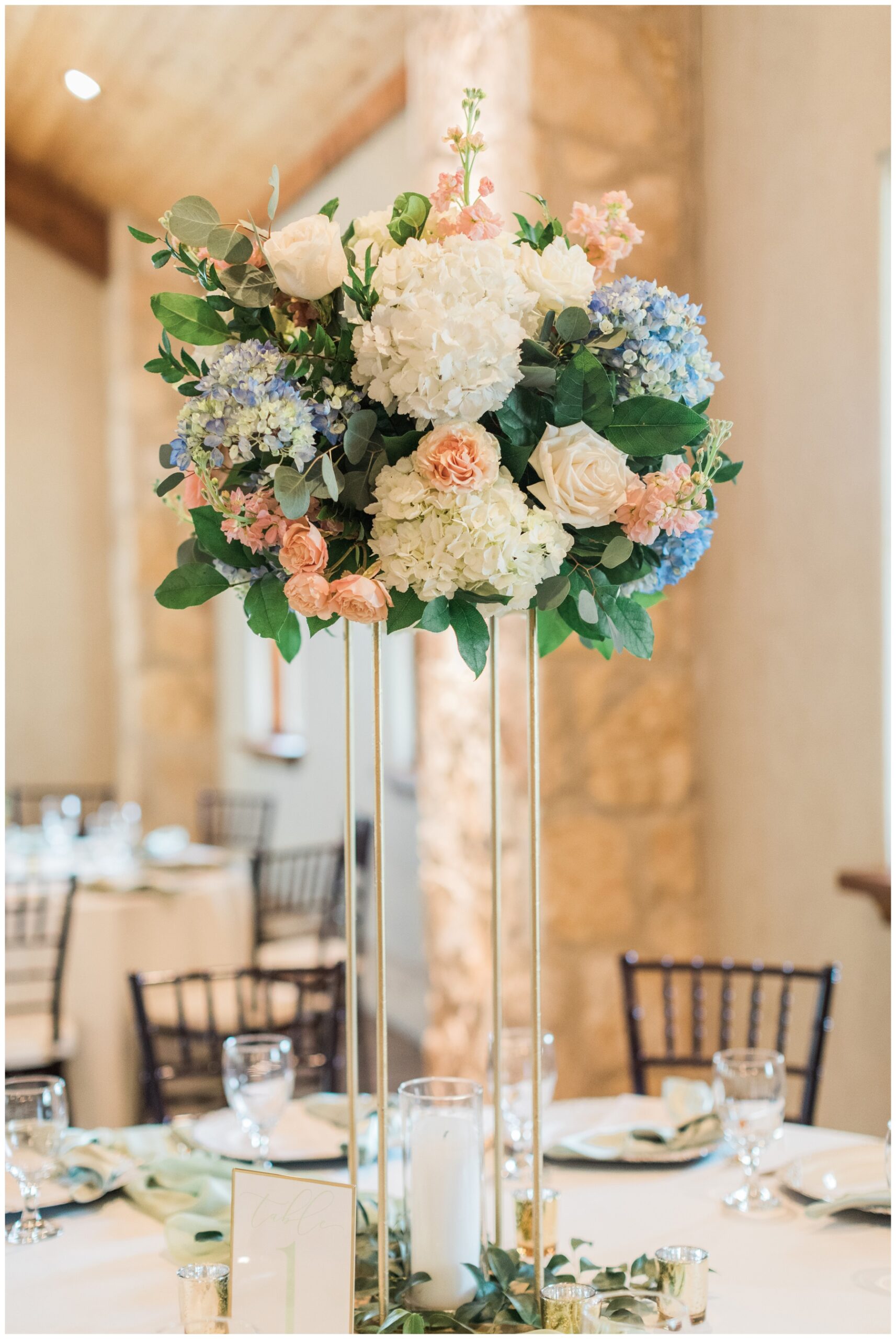 Tall floral centerpiece with blue and white hydrangeas and blush roses at a wedding