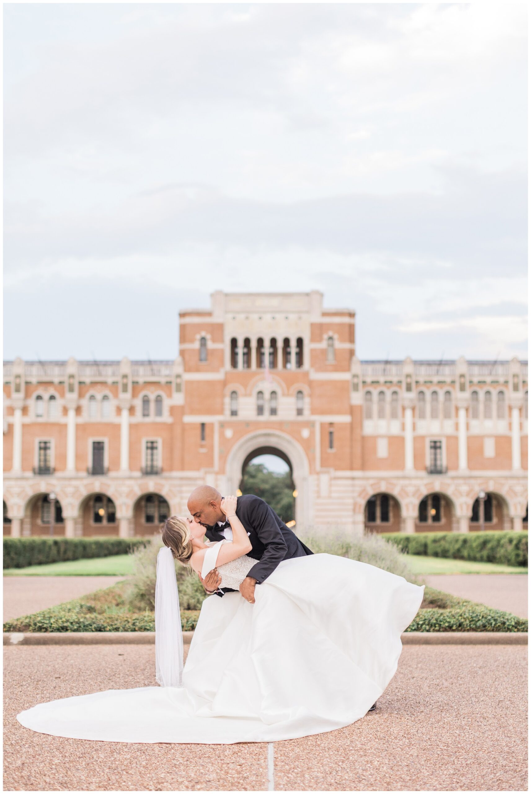 Bride and groom kissing in front of Lovett Hall at Rice University